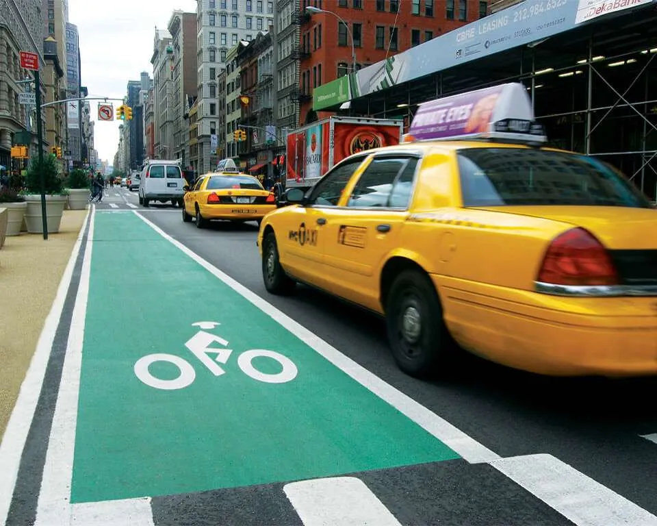 Green bike lane with a white bicycle symbol beside a city street
