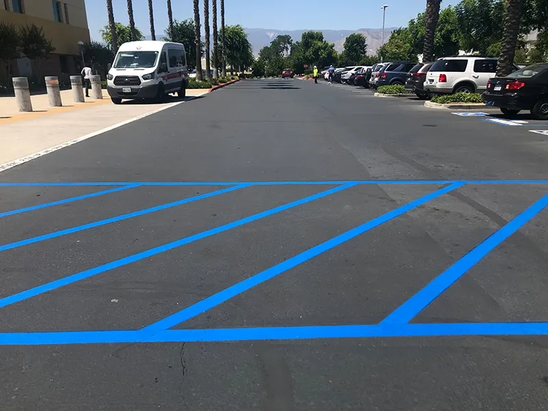 Parking lot with bright blue stall lines on dark asphalt
