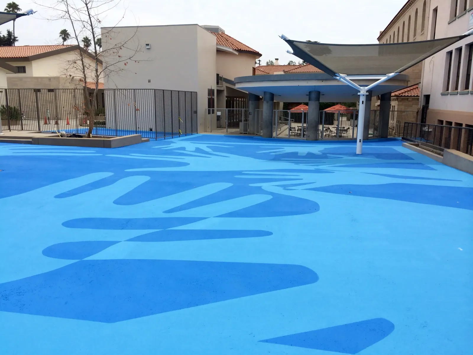 Schoolyard pavement coated in two shades of blue with a large decorative pattern