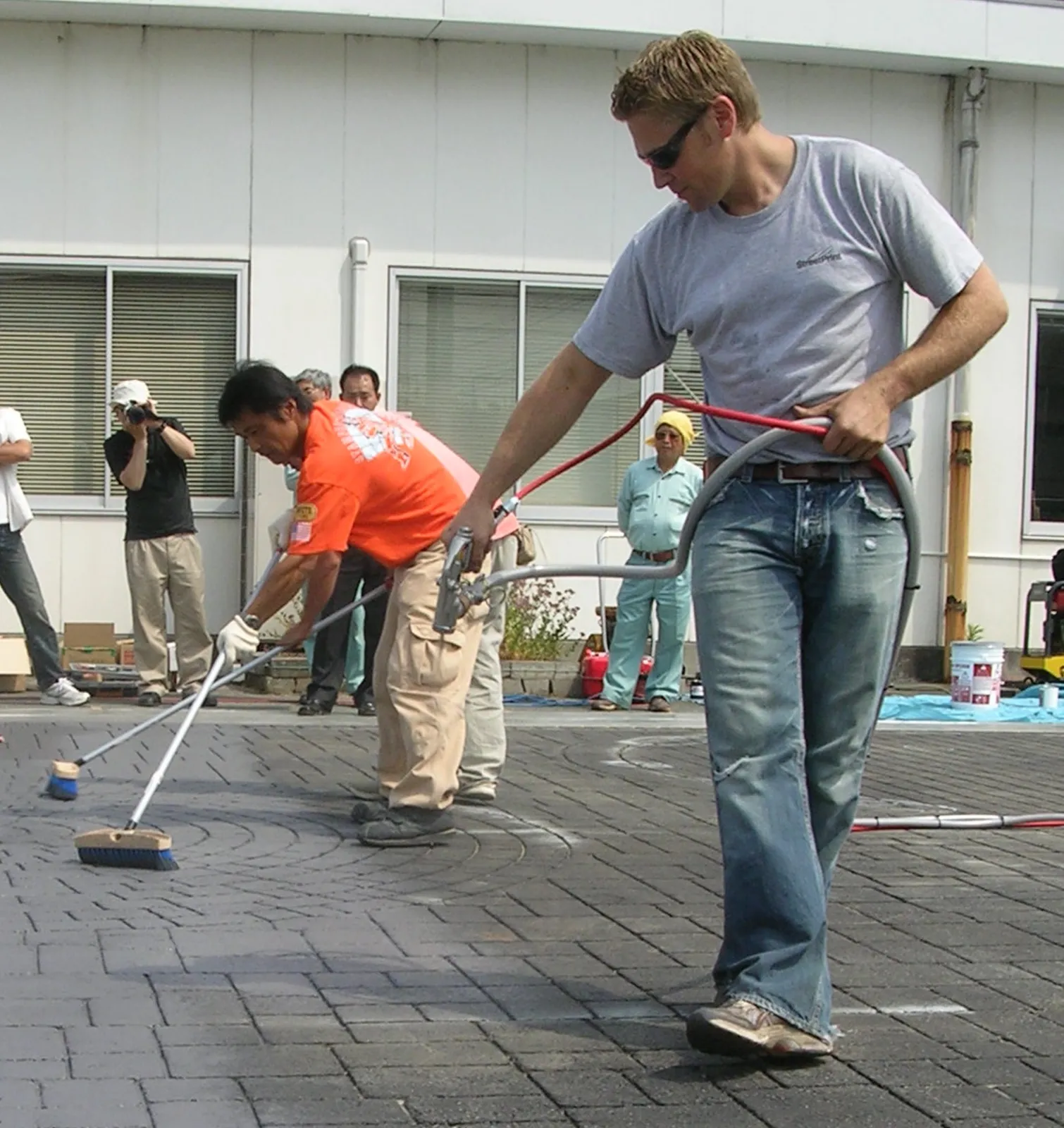 Applicators coating stamped asphalt with a brick pattern